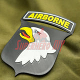3D-printed 101st Airborne Division display insignia on green fabric background.
