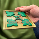 Hand holding 3D-printed 4th Infantry Division display insignia in green and gold, ideal for home or office decoration.