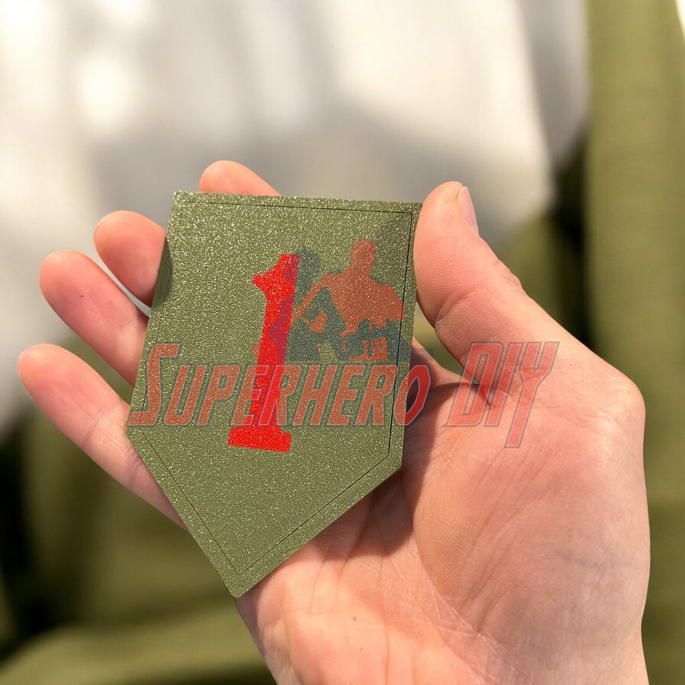 Hand holding 1st Infantry Division display insignia, Big Red One patch, olive green background, perfect for wall display or shadowbox.