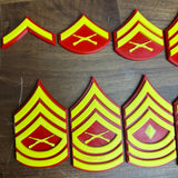 USMC enlisted rank insignia in red and yellow, showcasing multiple Marine Corps ranks, including Private First Class to Sergeant Major.