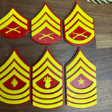 USMC enlisted rank insignias in red and yellow, featuring various Marine Corps designs.