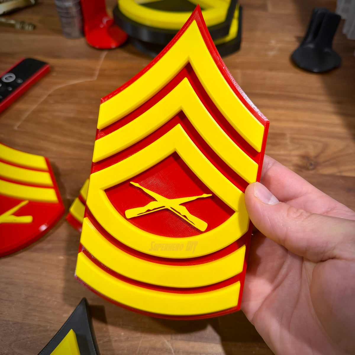 Hand holding a red and yellow USMC enlisted rank insignia, showcasing detailed 3D printing for Marine Corps pride.