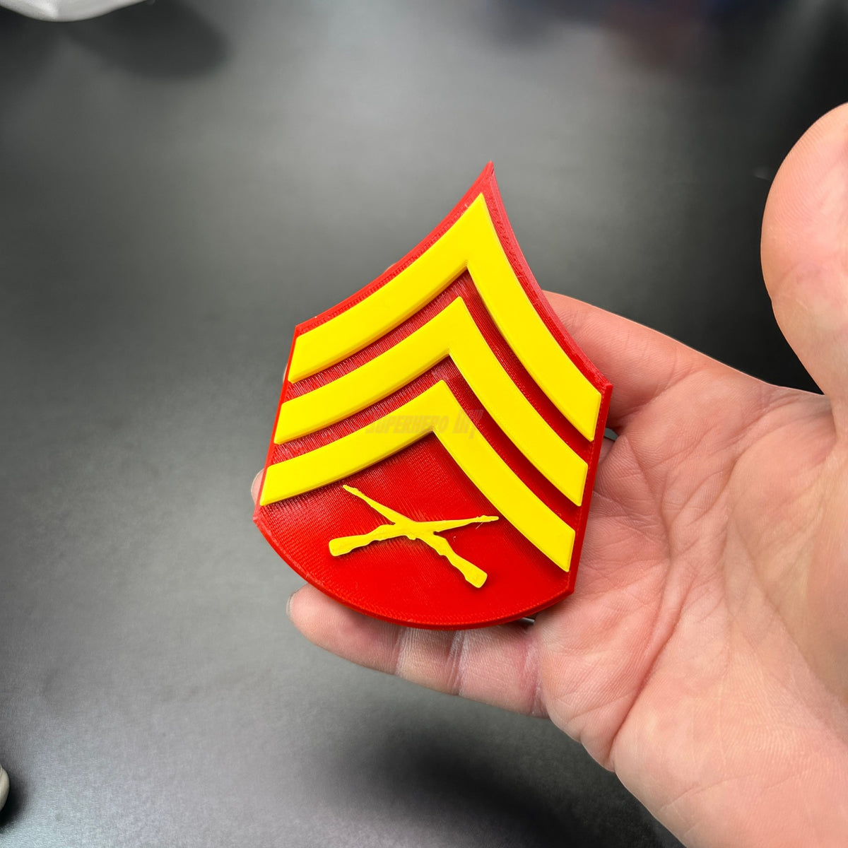 Detailed USMC enlisted rank insignia patch in red and yellow, showcasing the Marine Corps NCO rank.