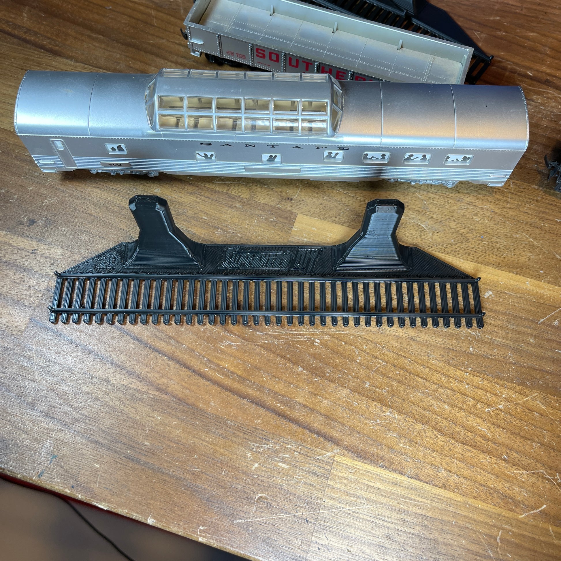 Black HO-scale train display shelf with model train car on wooden table.