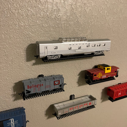 Floating HO-scale train display shelf featuring various HO scale train cars on a wall.