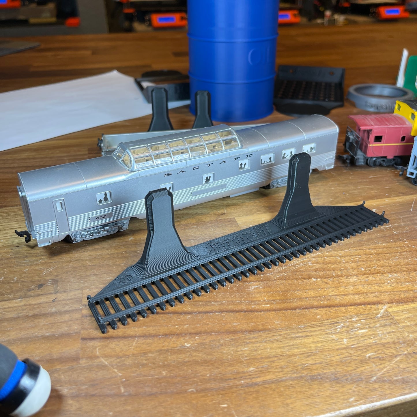 HO-scale train display shelf with a model train on a wooden surface, showcasing a realistic track design.