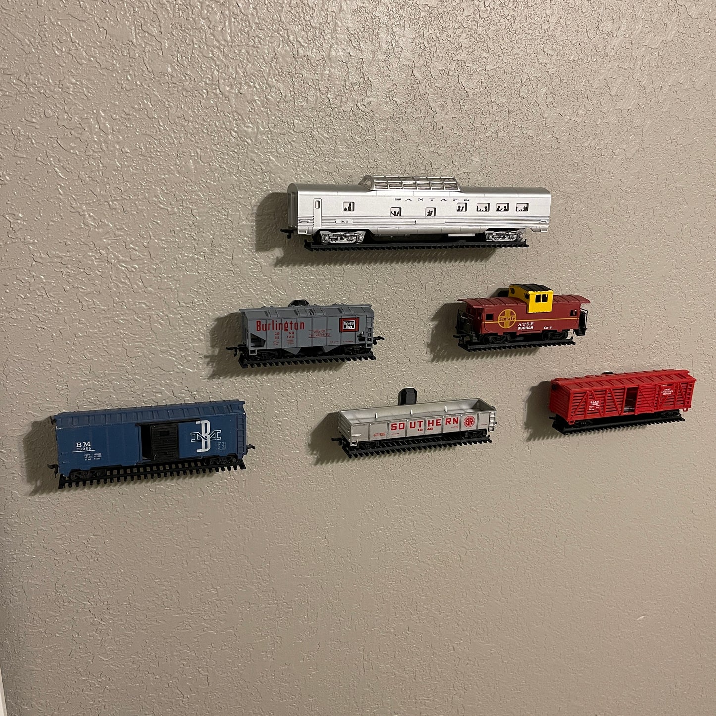 HO-scale train display shelf featuring various colorful train cars mounted on wall