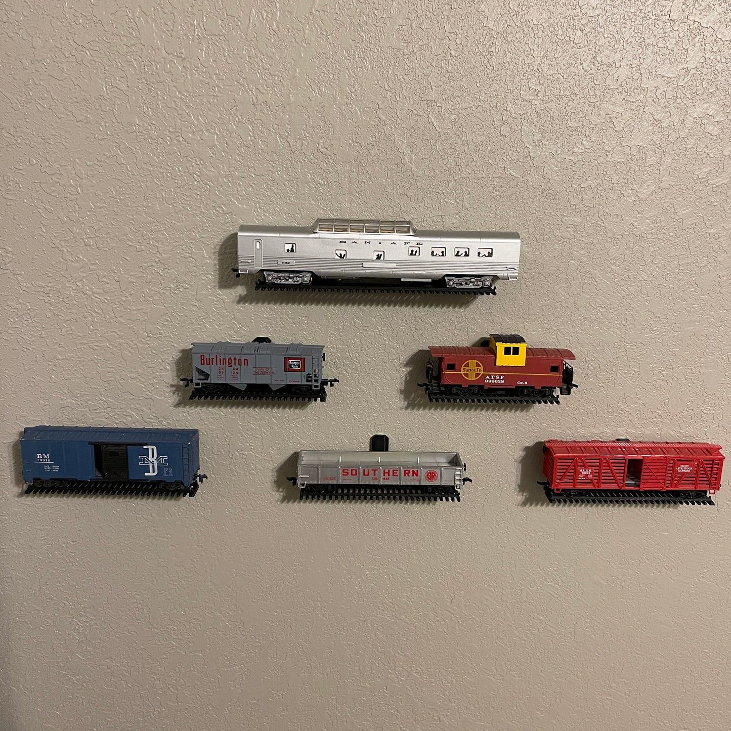 HO-scale train display shelf featuring various train cars mounted on the wall.