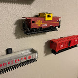 HO-scale train display shelf featuring colorful model train cars mounted on the wall.
