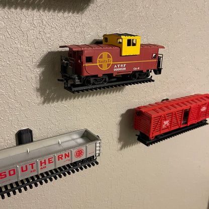 HO-scale train display shelf featuring colorful model train cars mounted on the wall.
