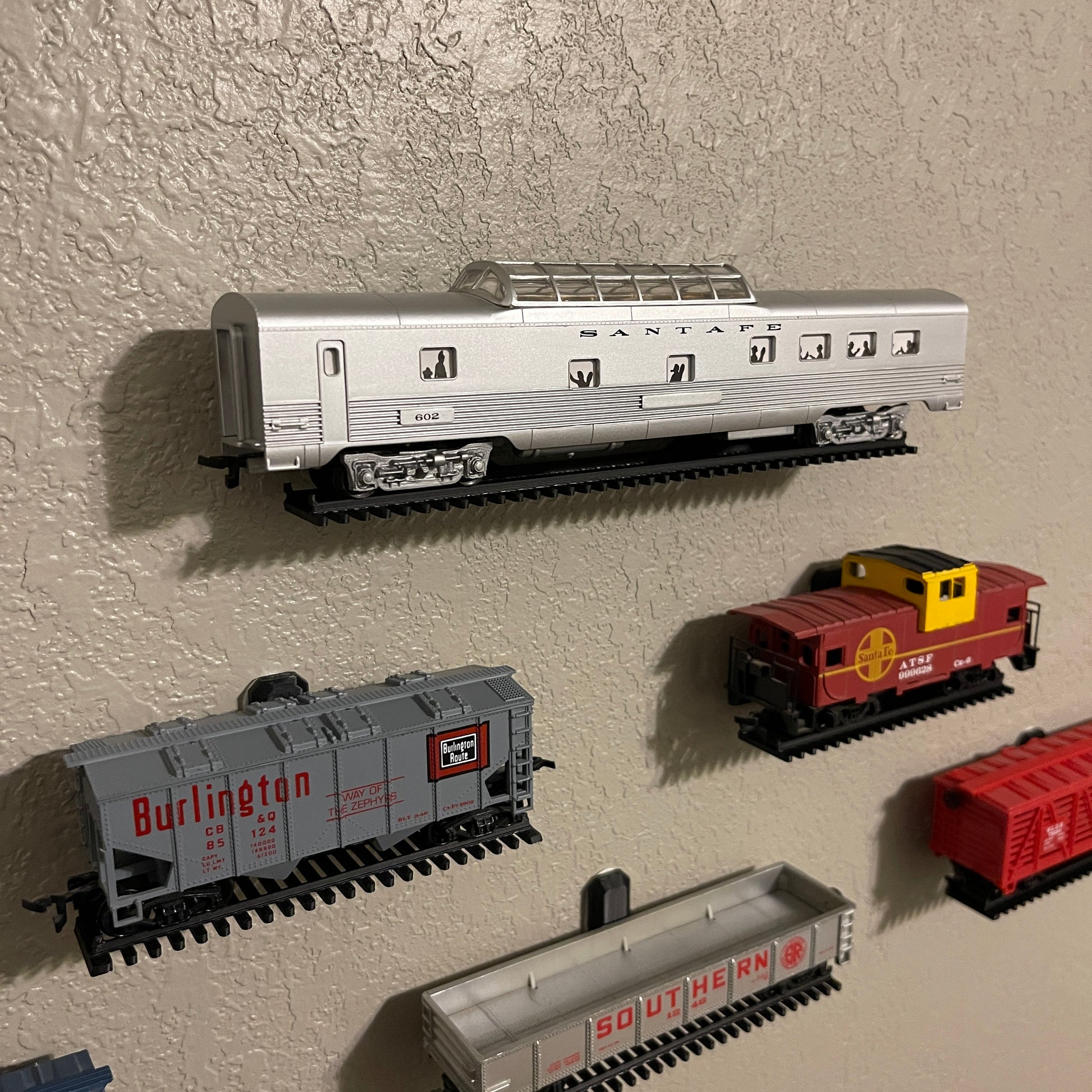 HO-scale train display shelf showcasing various model train cars on a wall.
