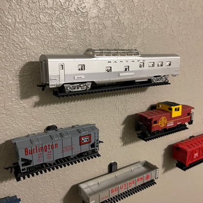 HO-scale train display shelf showcasing various model train cars on a wall.